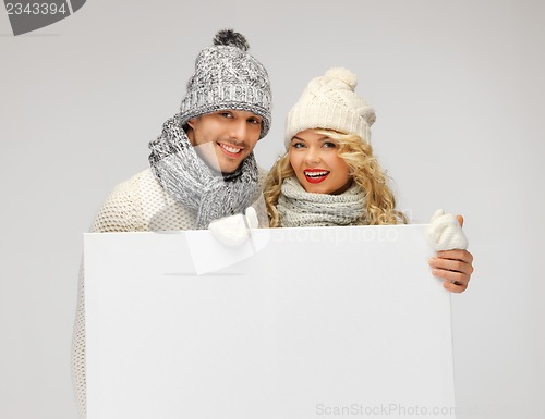 Image of couple in a winter clothes holding blank board