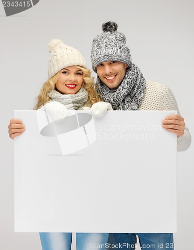 Image of couple in a winter clothes holding blank board