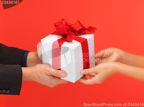 Image of man and woman's hands with gift box