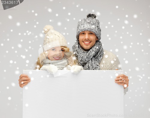 Image of couple in a winter clothes holding blank board