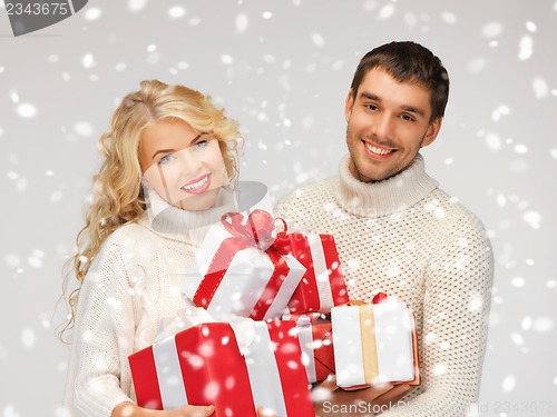 Image of family couple in a sweaters with gift boxes