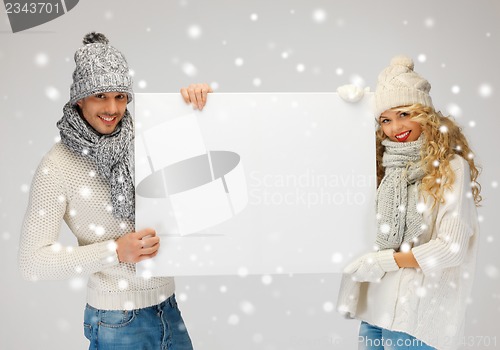 Image of couple in a winter clothes holding blank board