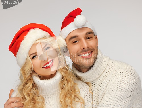 Image of family couple in sweaters and santa's hats