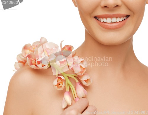 Image of woman's shoulder and hands holding orchid flower