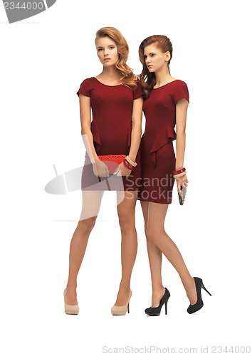 Image of two teenage girls in red dresses with clutches