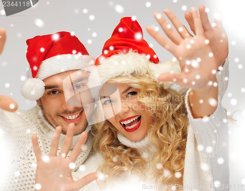 Image of family couple in sweaters and santa's hats