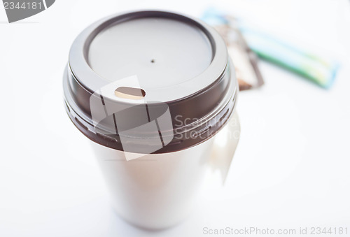 Image of Hot coffee in paper cup with sugar packs on white background