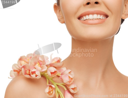 Image of smiling woman with orchid flower on her shoulder