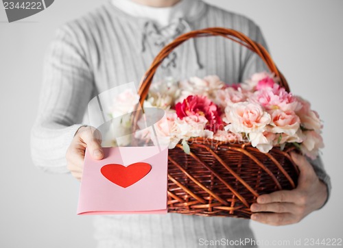 Image of man holding basket full of flowers and postcard