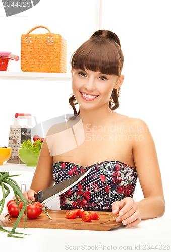 Image of beautiful woman in the kitchen cutting vegetables