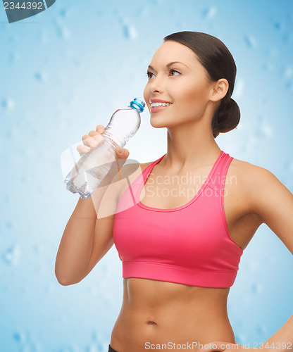 Image of sporty woman drinking water from bottle