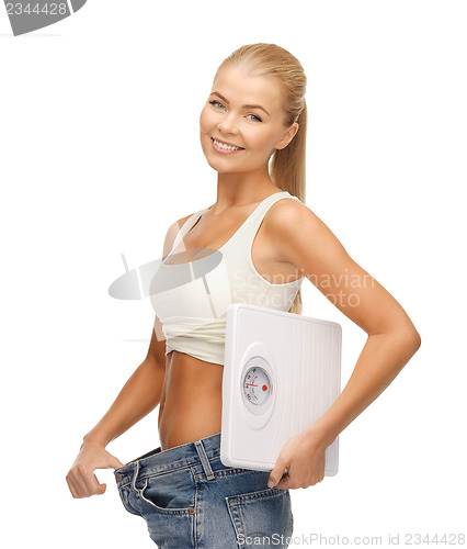 Image of woman showing big pants and holding scales