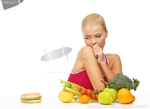 Image of doubting woman with fruits and hamburger