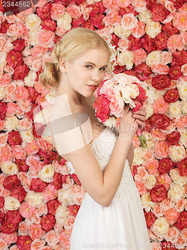 Image of woman with bouquet and background full of roses