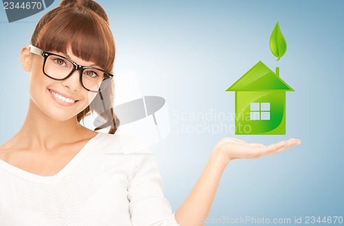 Image of woman holding green house in her hands