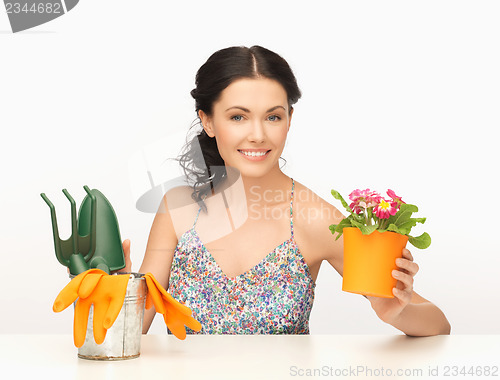 Image of housewife with flower in pot and gardening set