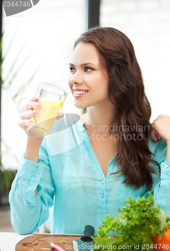 Image of young woman holding glass of orange juice