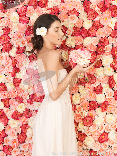 Image of woman with bouquet and background full of roses