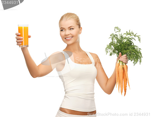 Image of woman holding glass of juice and carrots