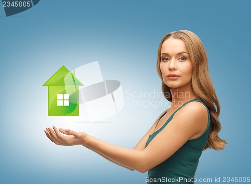 Image of woman holding green house in her hands