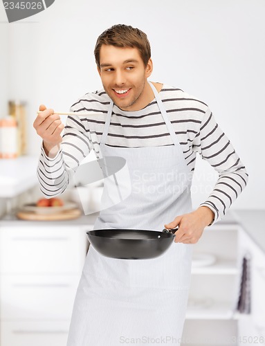 Image of handsome man with pan at kitchen