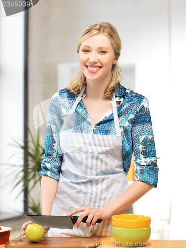 Image of beautiful woman in the kitchen cutting an apple