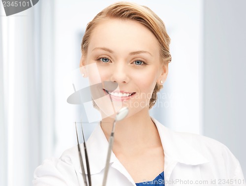 Image of attractive female dentist with tools