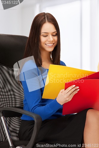 Image of young businesswoman with folders sitting in chair