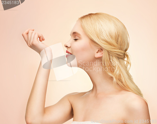 Image of young girl smelling pefrume on her hand