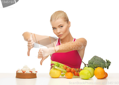 Image of woman with fruits showing thumbs down to cake