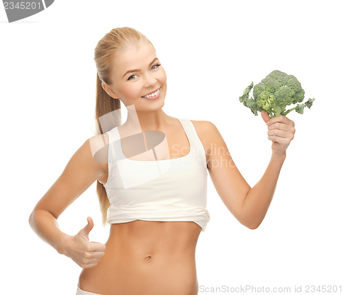 Image of woman pointing at her abs and holding broccoli