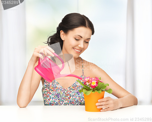 Image of housewife with flower in pot and watering can