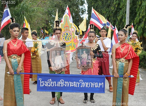 Image of Thai youth in traditional clothing hold photographs of the King