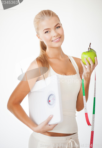Image of sporty woman with scale, apple and measuring tape