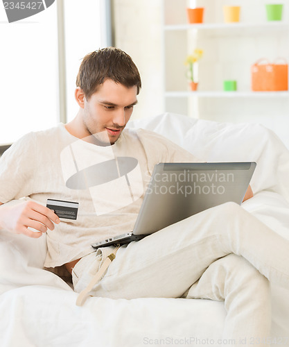 Image of young man with laptop and credit card at home