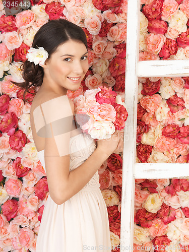 Image of woman with bouquet and background full of roses