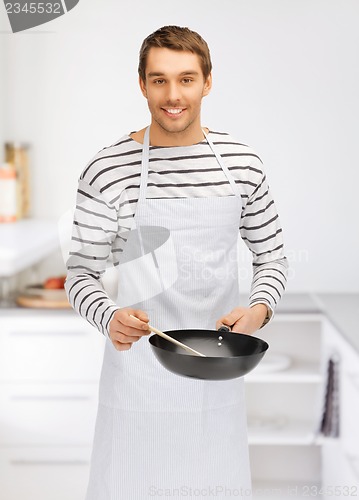 Image of handsome man with pan at kitchen