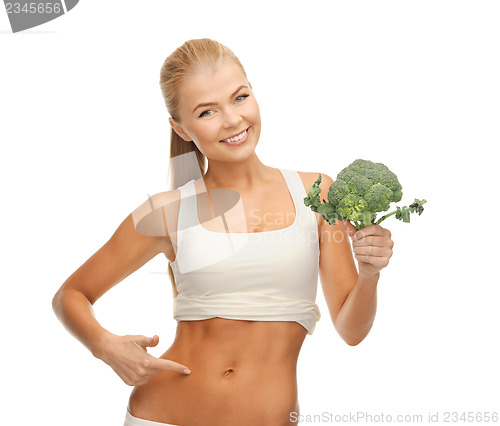 Image of woman pointing at her abs and holding broccoli