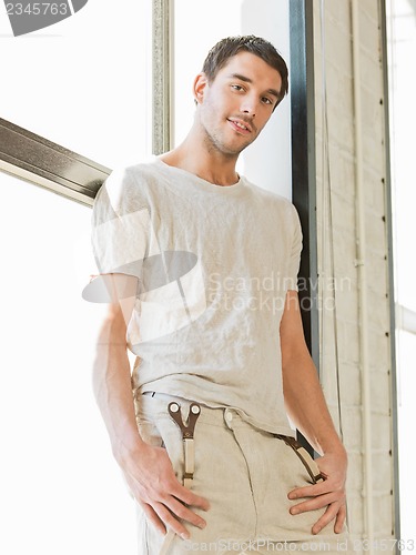 Image of handsome man standing on the windowsill