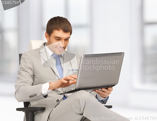 Image of young businessman sitting in chair with laptop