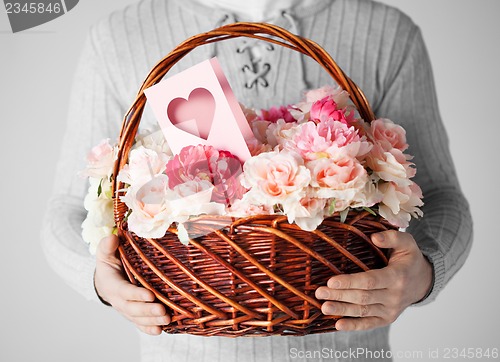 Image of man holding basket full of flowers and postcard