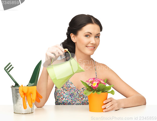 Image of housewife with flower in pot and watering can