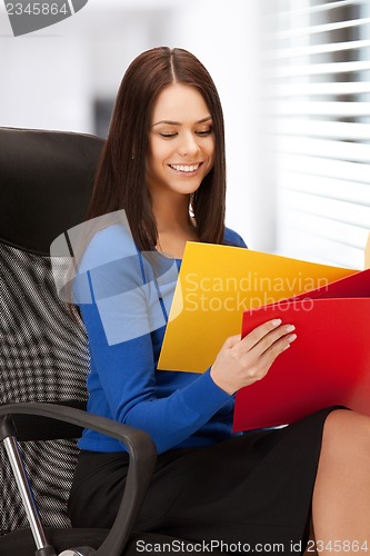 Image of young businesswoman with folders sitting in chair