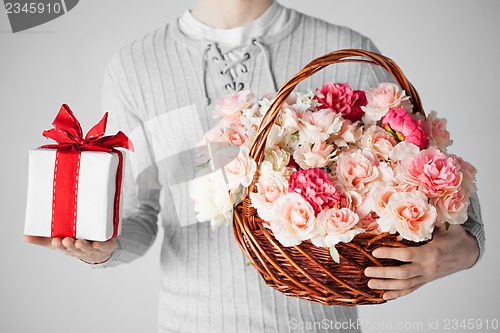 Image of man holding basket full of flowers and gift box