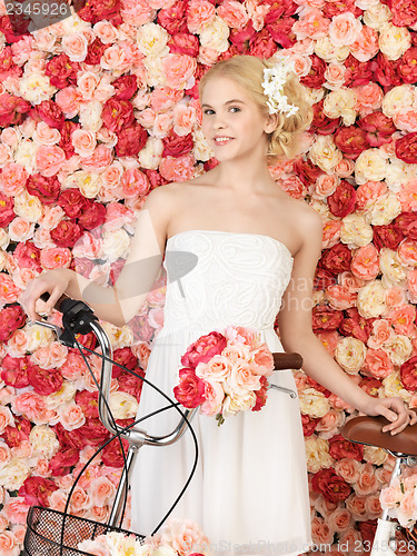 Image of woman with bicycle and background full of roses