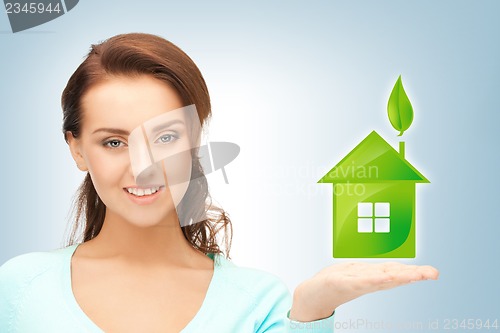 Image of woman holding green house in her hands