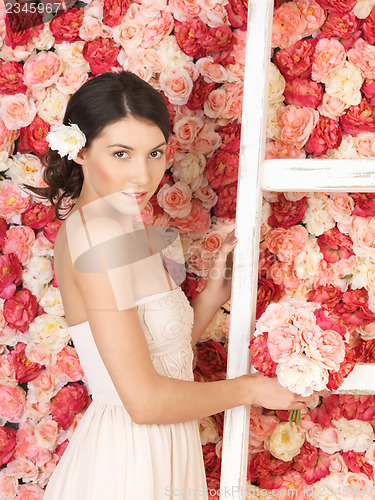 Image of woman with bouquet and background full of roses