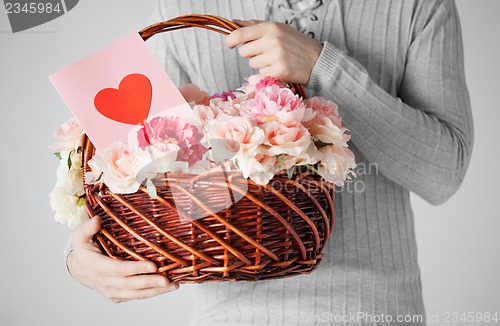 Image of man holding basket full of flowers and postcard