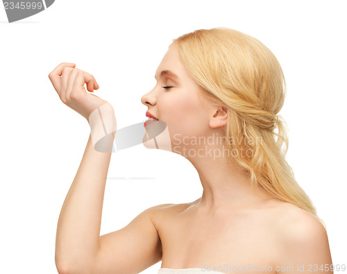 Image of young girl smelling pefrume on her hand