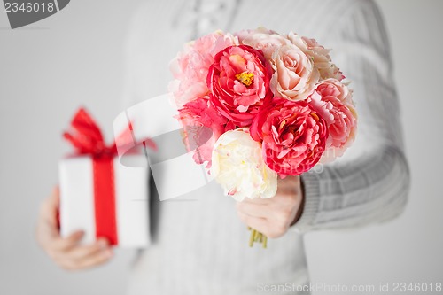 Image of man holding bouquet of flowers and gift box